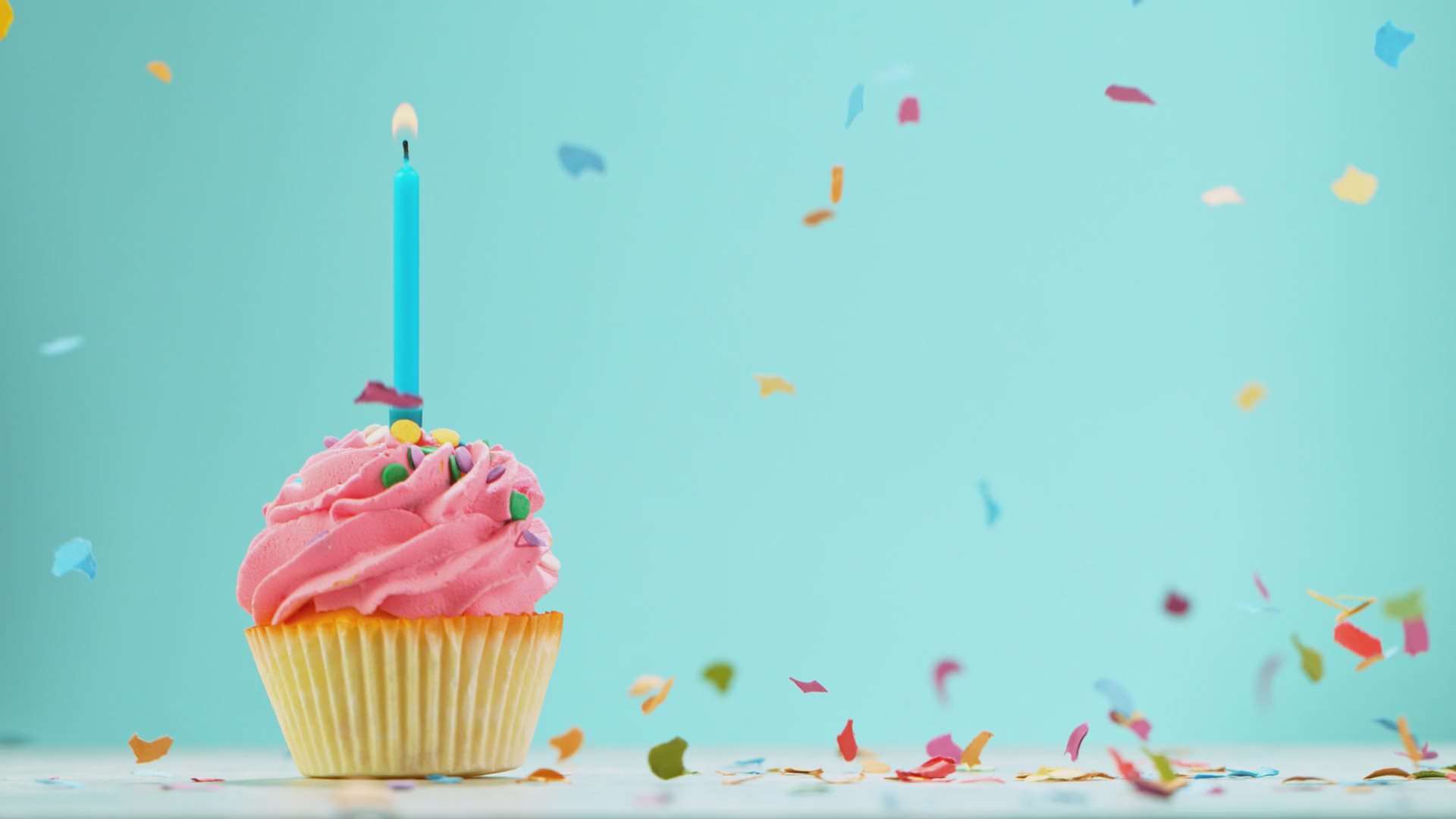 Video of a Birthday cupcake with burning candle and flying confetti