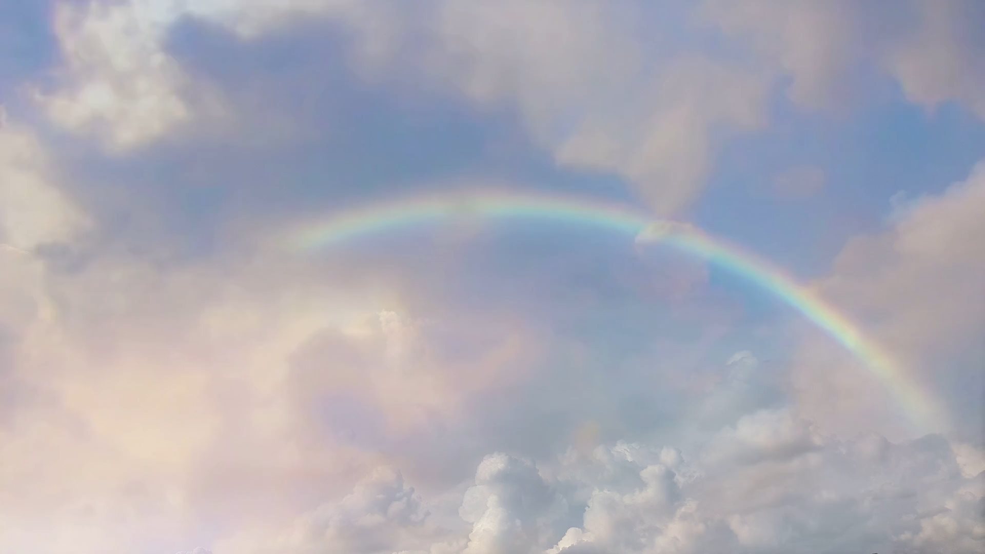 Video of a rainbow with clouds flying by