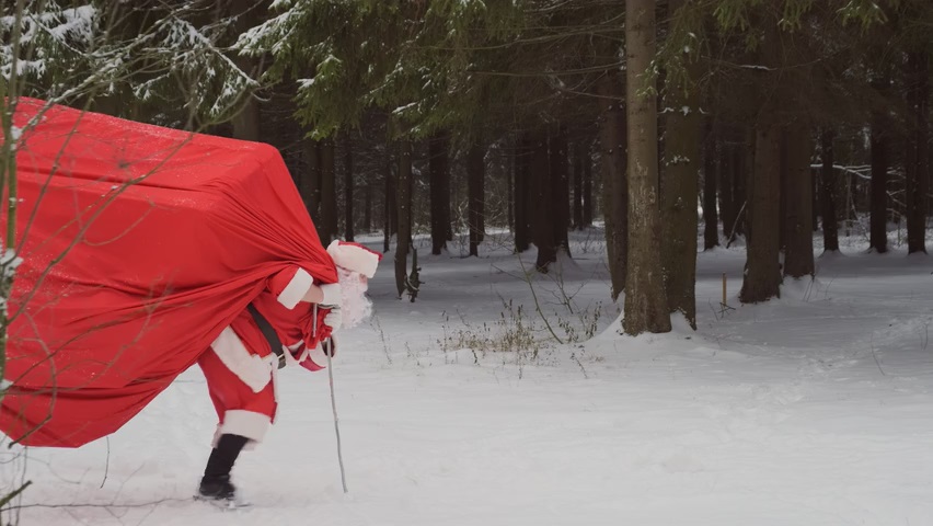 Video vom Weihnachtsmann, der einen sehr großen und schweren Geschenkesack kaum tragen kann